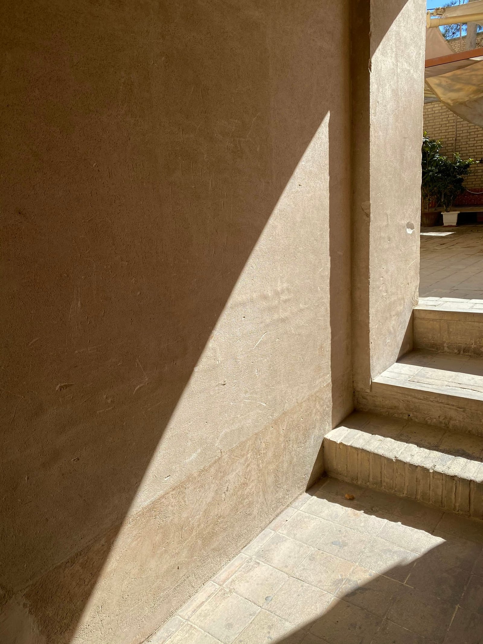 A pale stone staircase rising against a warm plaster wall